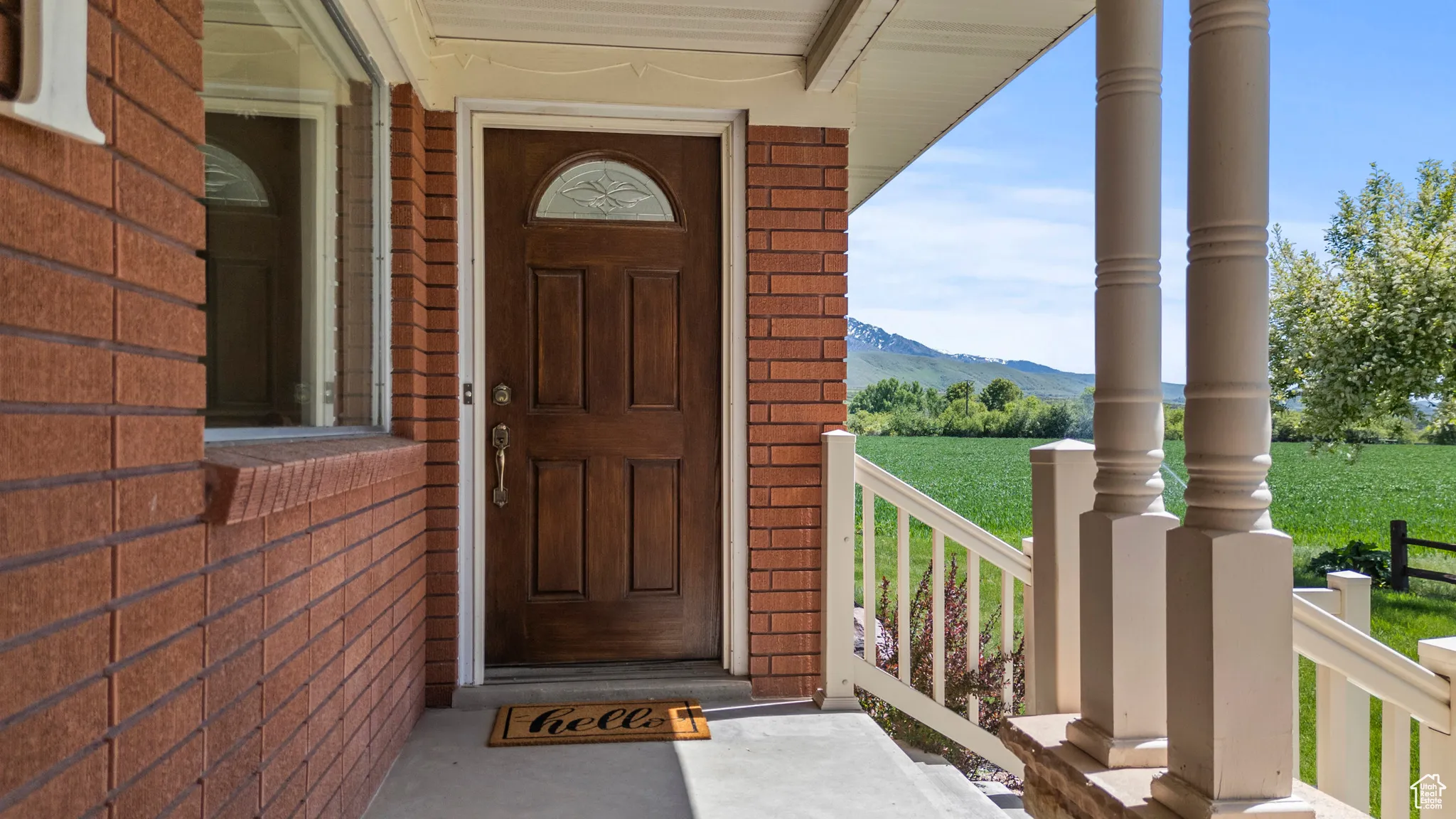 Doorway to property with brick siding, a porch, and a mountain view