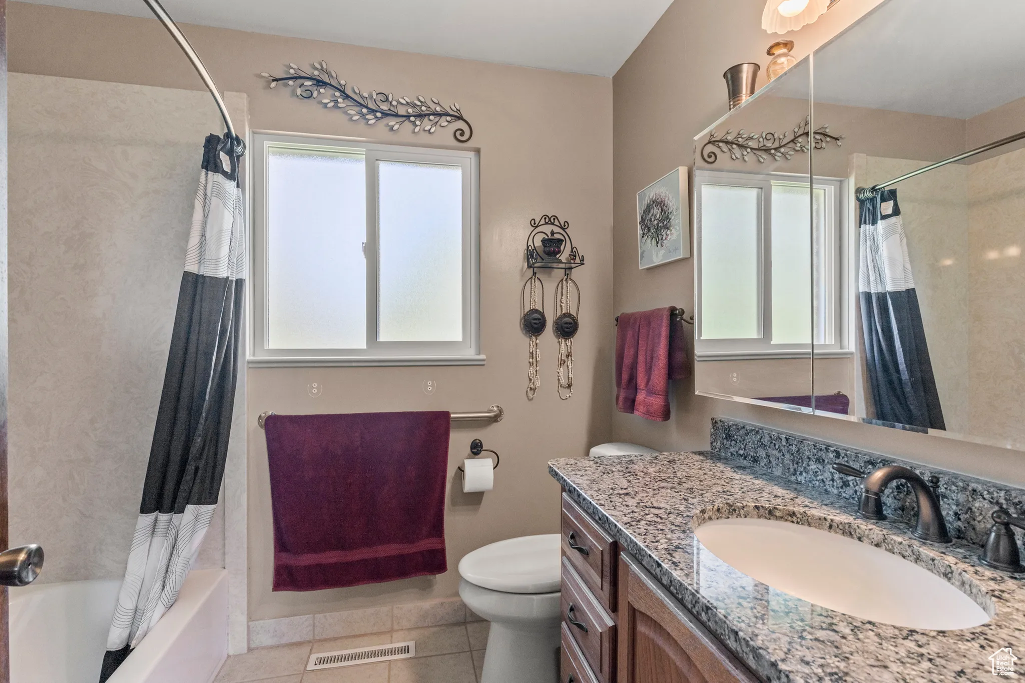 Full bathroom with tile patterned flooring, toilet, vanity, and shower / tub combo