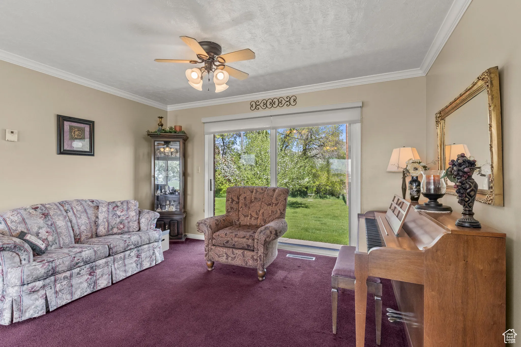 Carpeted living area featuring ornamental molding and a ceiling fan