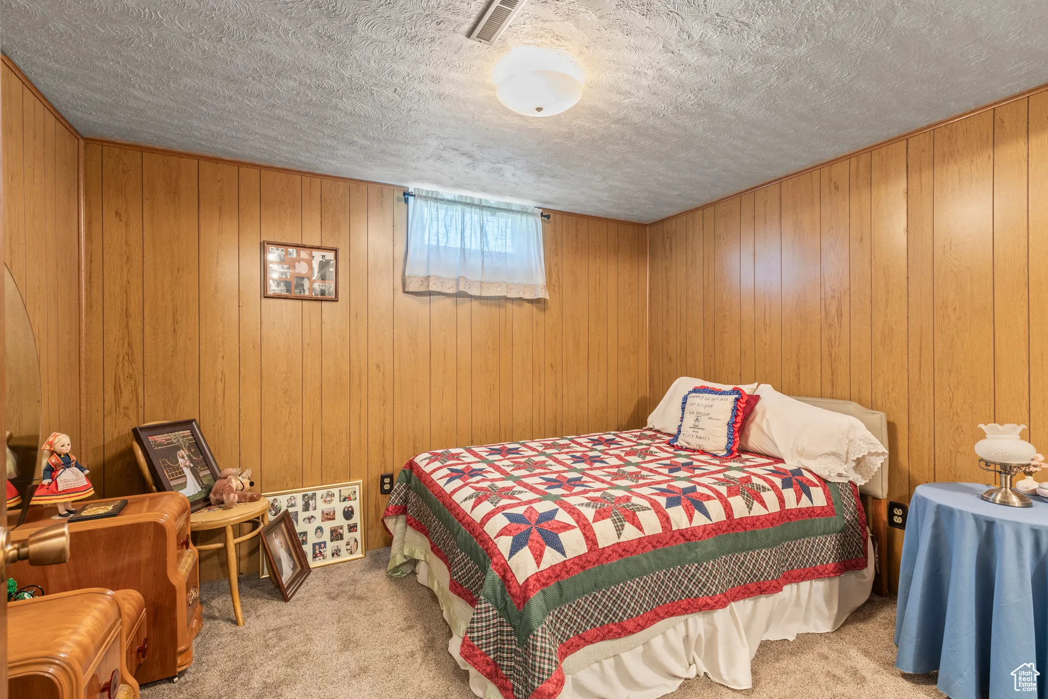 Bedroom with carpet flooring, a textured ceiling, and wooden walls