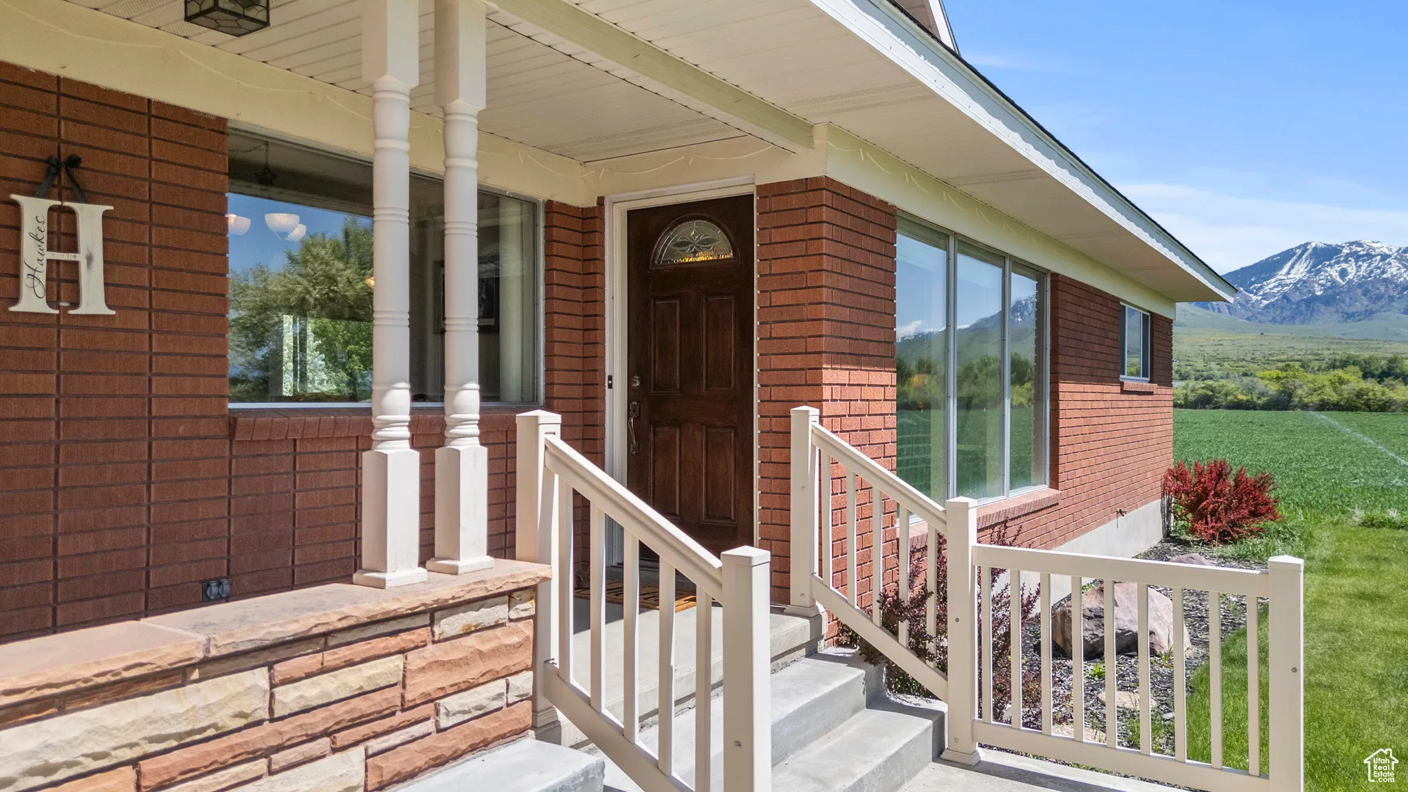 Entrance to property featuring brick siding, a mountain view, and covered porch