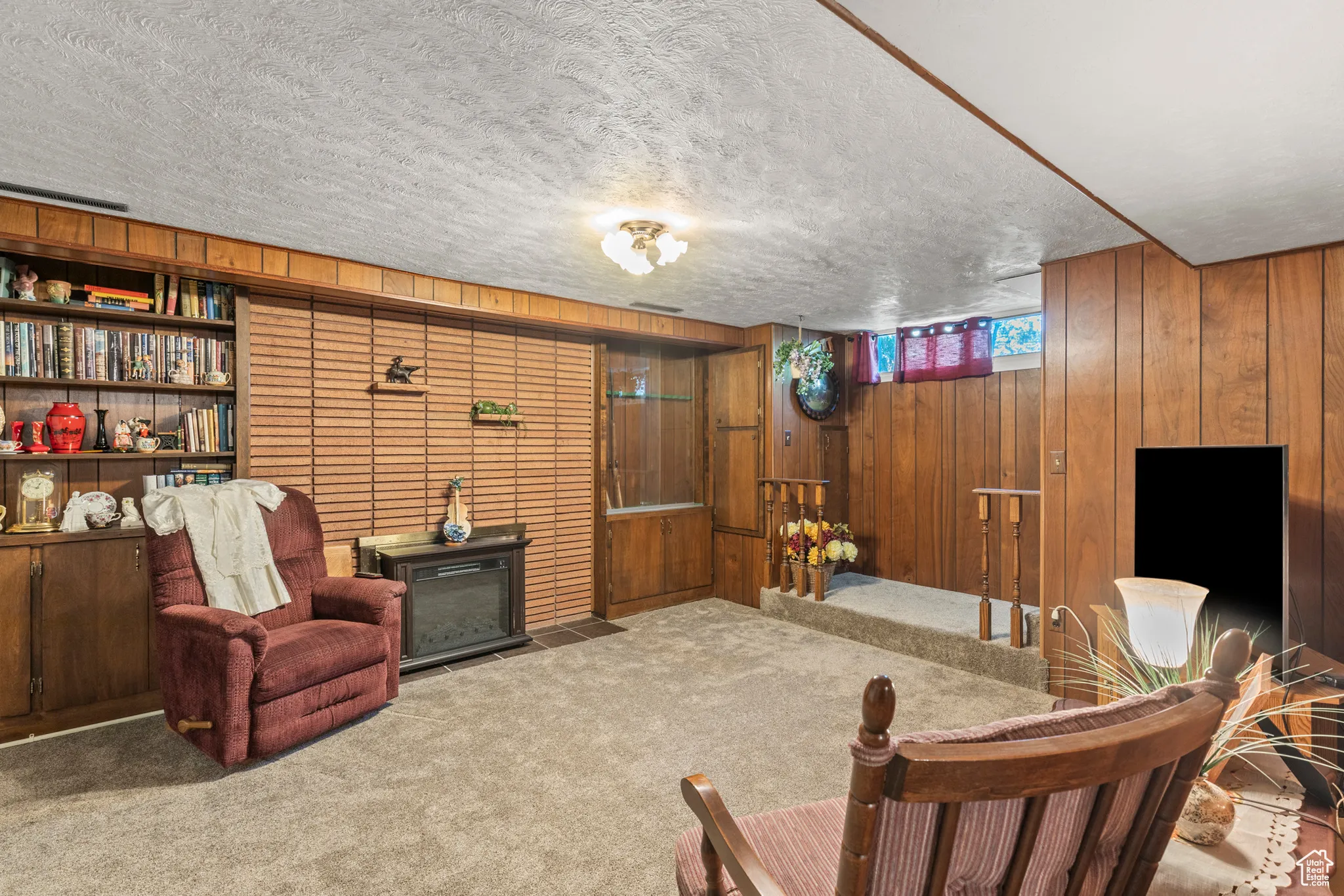 Sitting room featuring wood walls, carpet floors, and a textured ceiling