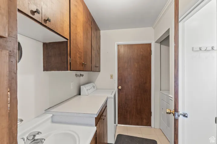 Clothes washing area featuring washer / clothes dryer and light tile patterned flooring