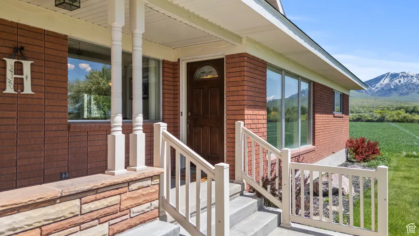 Entrance to property featuring brick siding, a mountain view, and covered porch