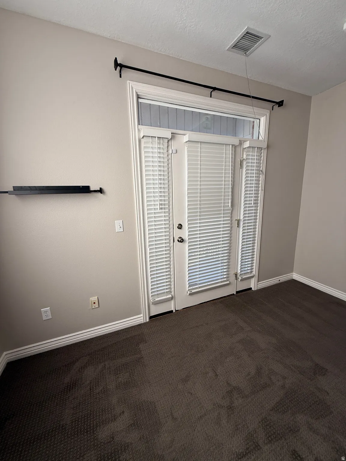 Suite 209 Empty room featuring dark colored carpet and a textured ceiling