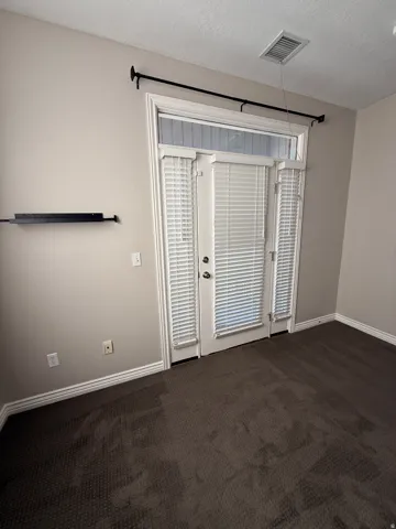 Suite 209 Empty room featuring dark colored carpet and a textured ceiling
