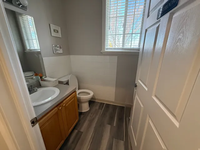 Shared Bathroom with vanity, dark wood-style floors, tile walls, a wainscoted wall, and plenty of natural light