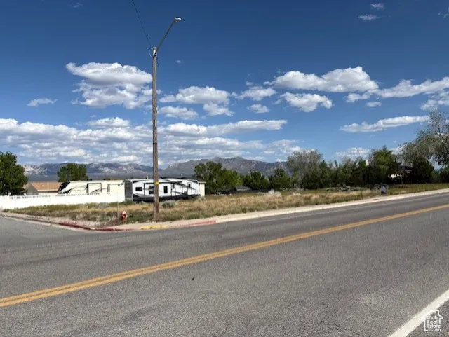 View of asphalt street with a mountain view, street lighting, and curbs