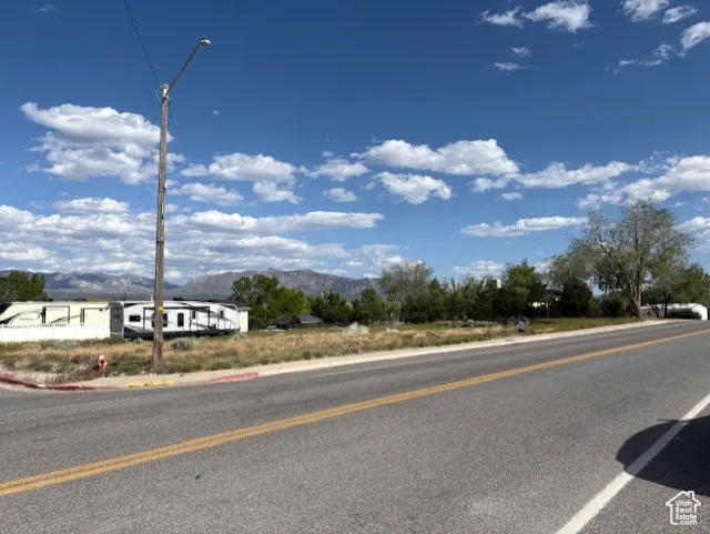 View of asphalt street with a mountain view, street lights, and curbs