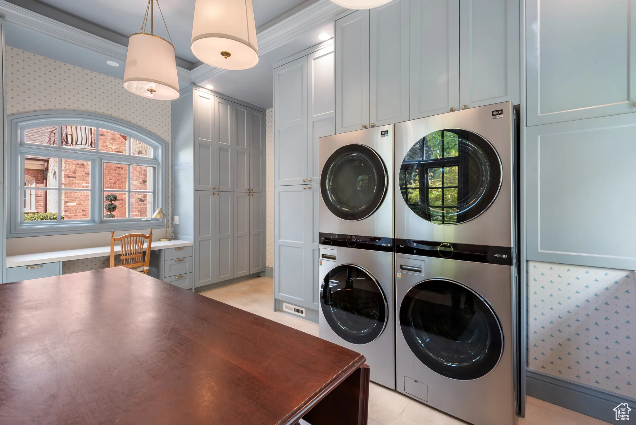 Clothes washing area featuring estacked washer and dryer, cabinet space, and crown molding