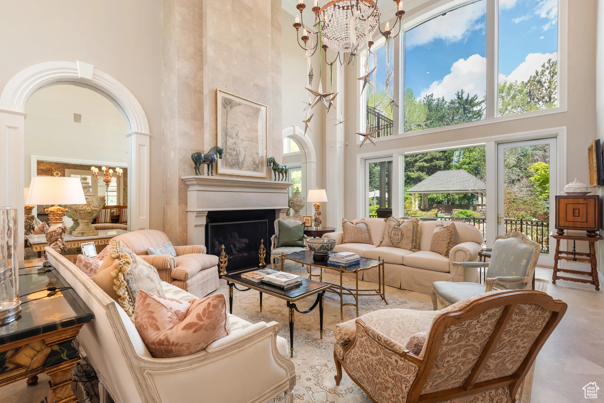 Living area featuring a high ceiling, a chandelier, a fireplace, and ornate columns
