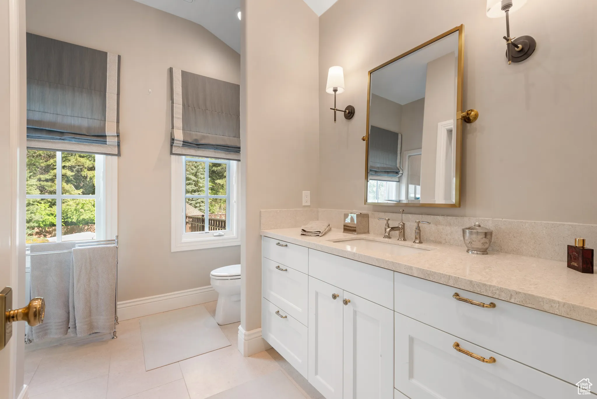 Bathroom with vanity, baseboards, toilet, and tile patterned flooring