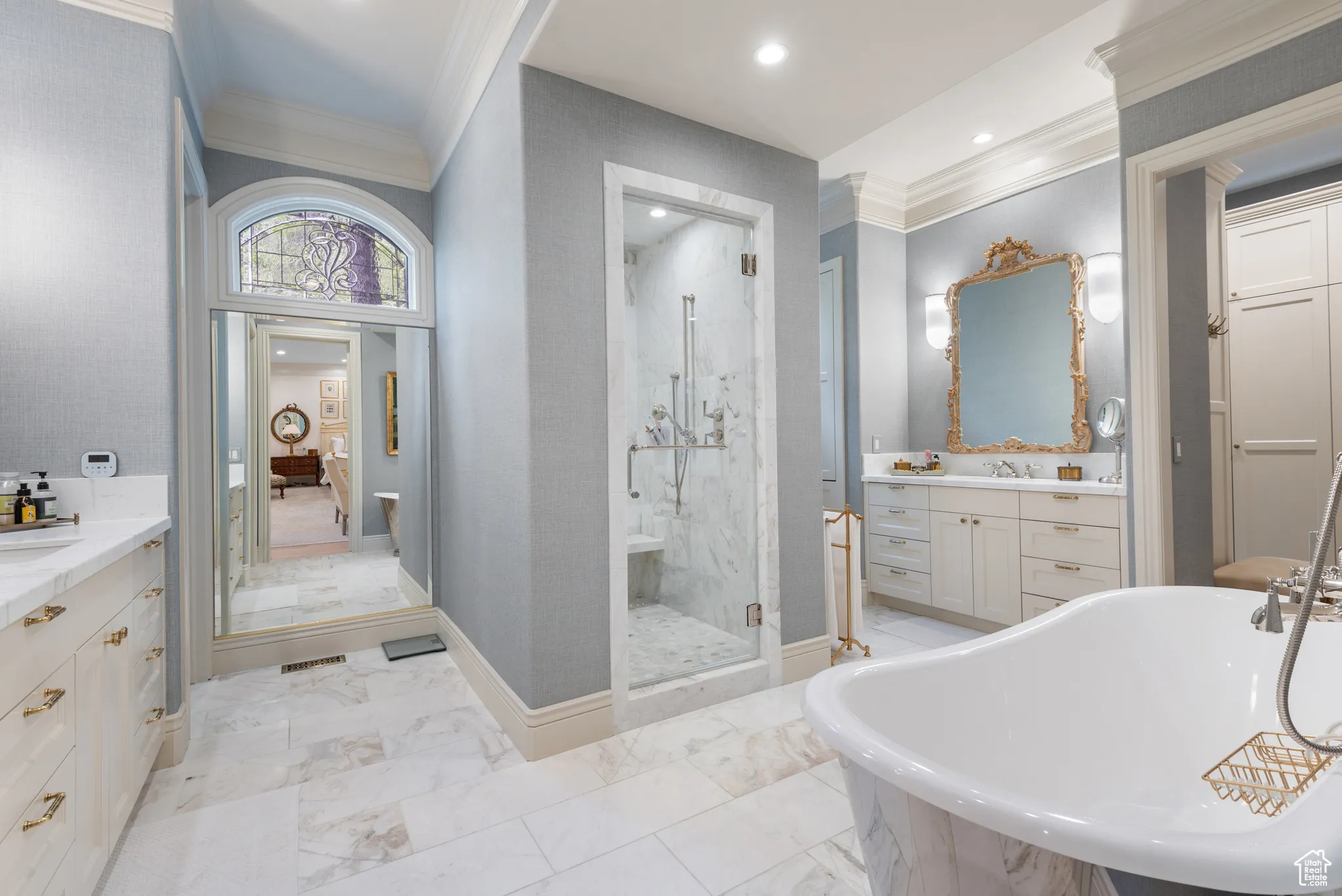 Bathroom featuring crown molding, a marble finish shower, vanity, a freestanding tub, and marble finish floors