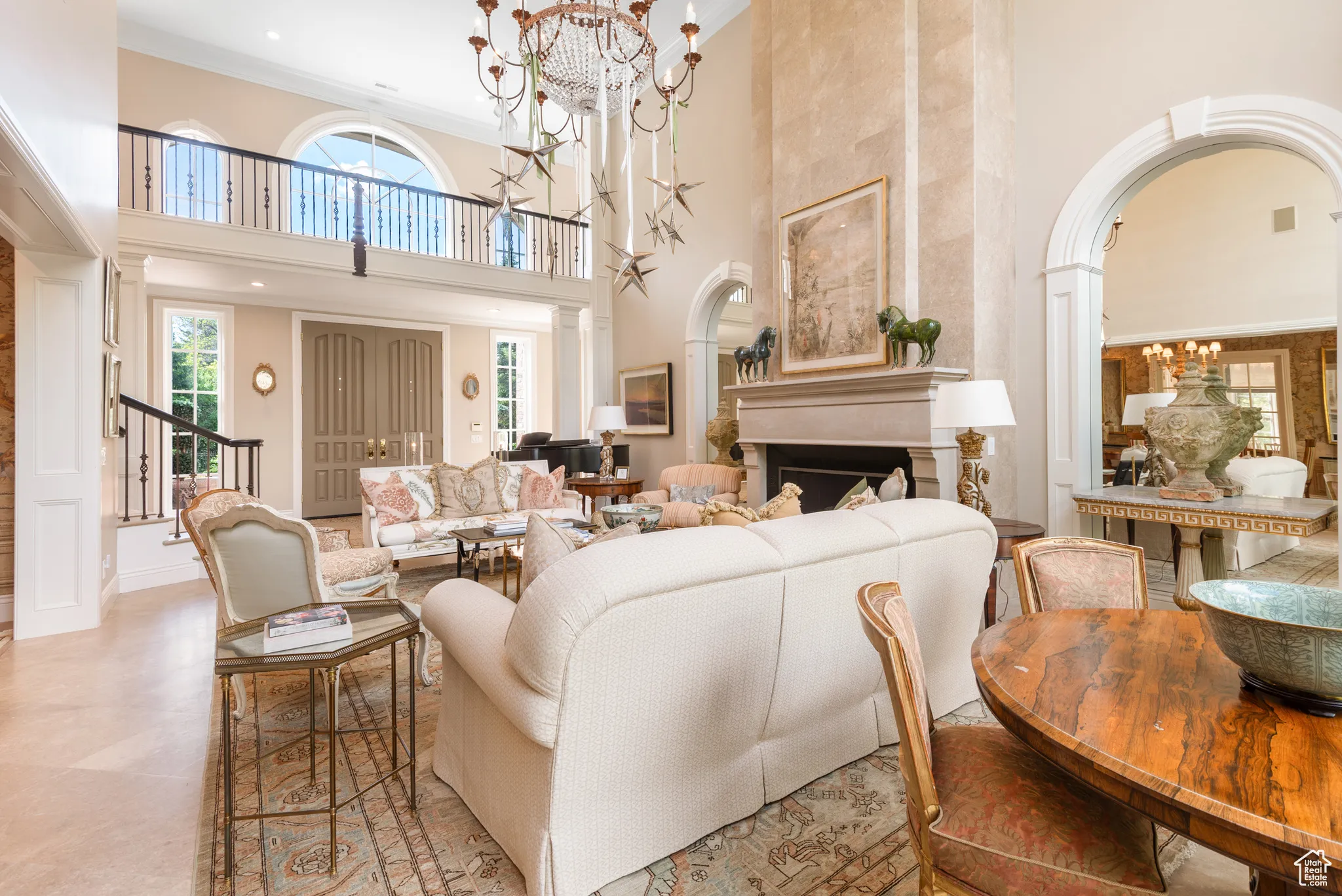 Living area with a towering ceiling, a chandelier, arched walkways, ornamental molding, and stairs