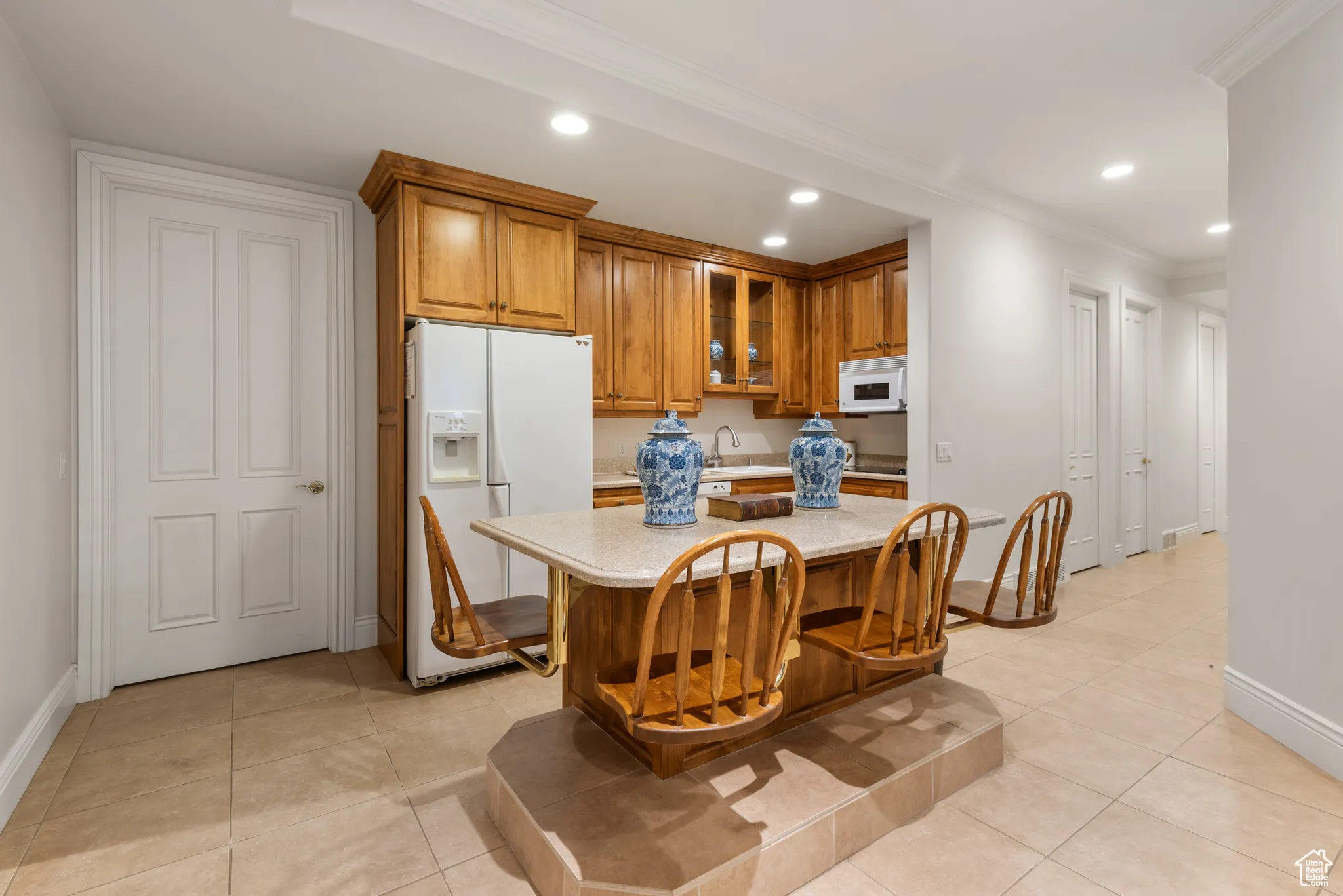 Kitchen with white appliances, brown cabinets, light countertops, recessed lighting, and baseboards