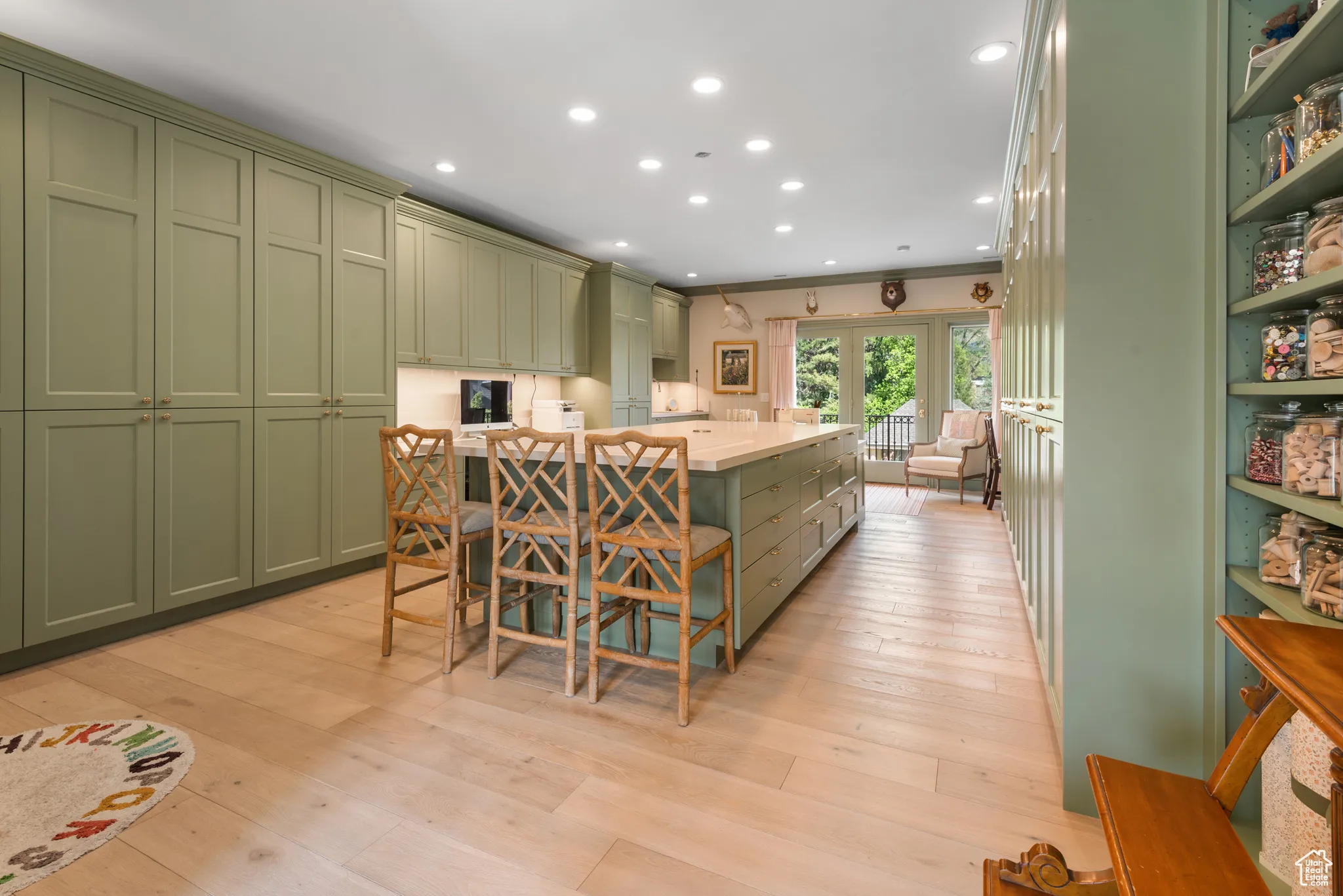 Kitchen with green cabinetry, recessed lighting, light wood-style floors, and a kitchen island