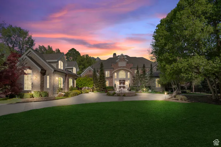 French country style house featuring a front lawn, curved driveway, and stone siding