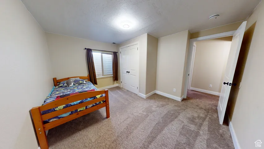 Carpeted bedroom with a textured ceiling and baseboards