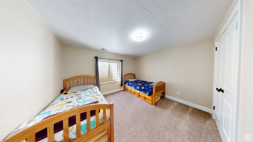 Bedroom featuring carpet, baseboards, and a textured ceiling