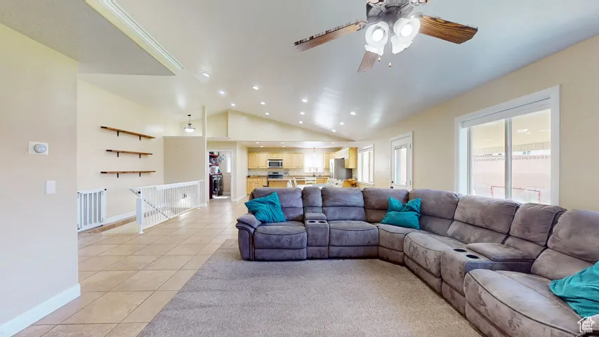 Living room featuring light tile patterned floors, recessed lighting, a ceiling fan, lofted ceiling, and baseboards