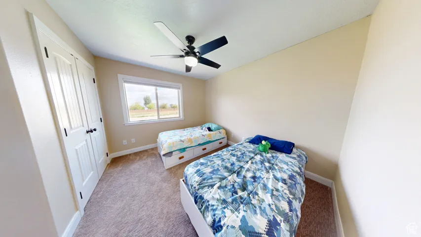 Carpeted bedroom with baseboards and a ceiling fan