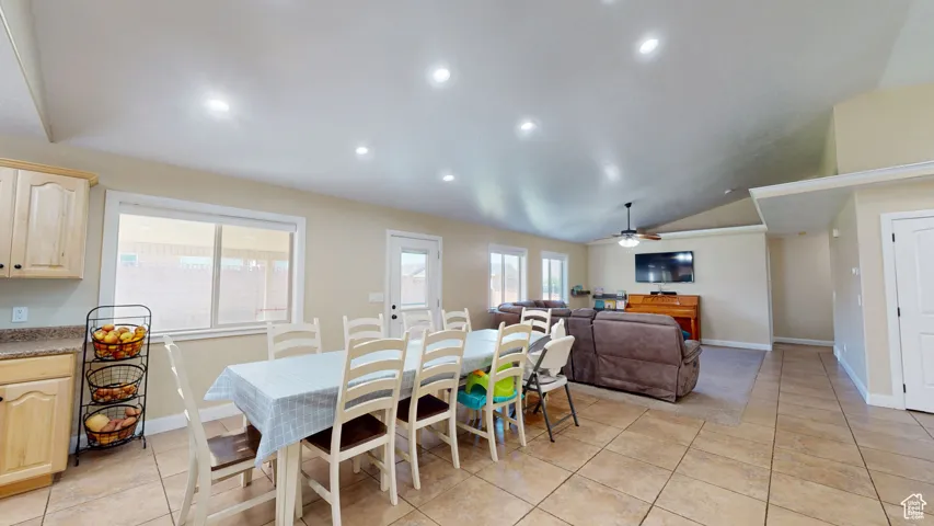 Dining space featuring a ceiling fan, vaulted ceiling, recessed lighting, baseboards, and light tile patterned floors