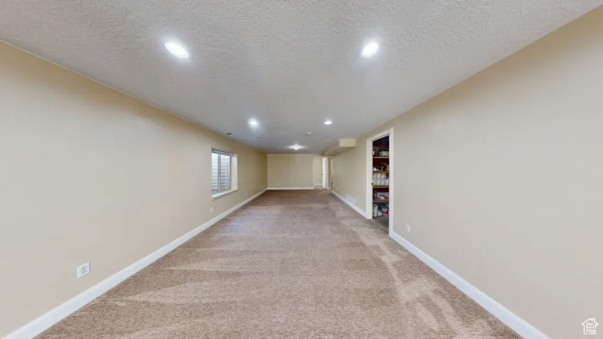 Basement featuring light colored carpet, recessed lighting, a textured ceiling, and baseboards
