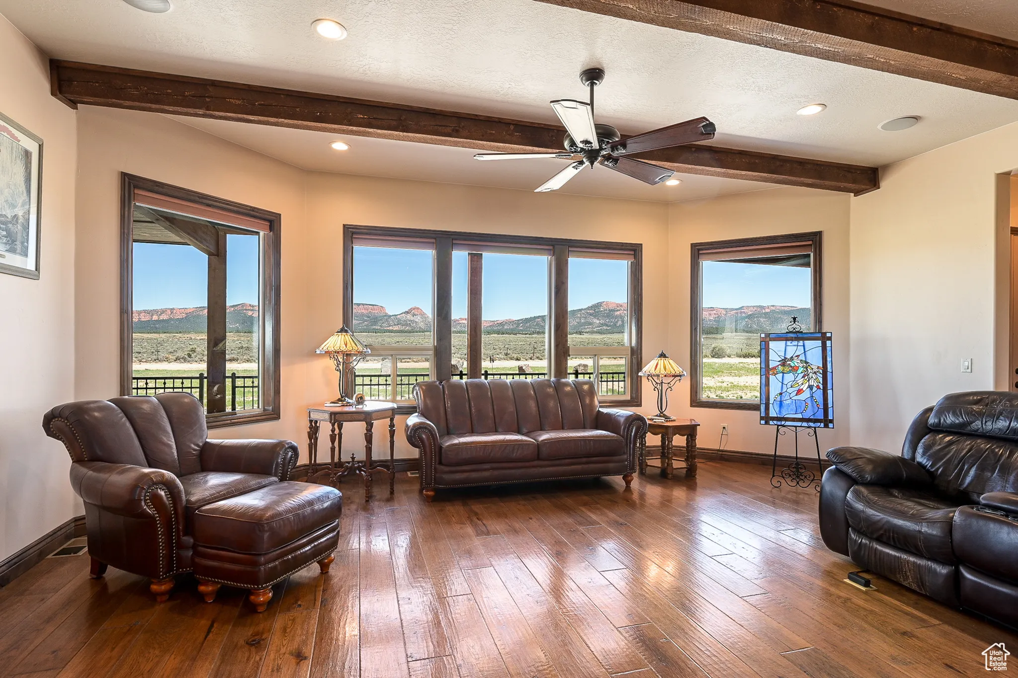 Living room with beamed ceiling, ceiling fan, baseboards, plenty of natural light, and hardwood / wood-style flooring