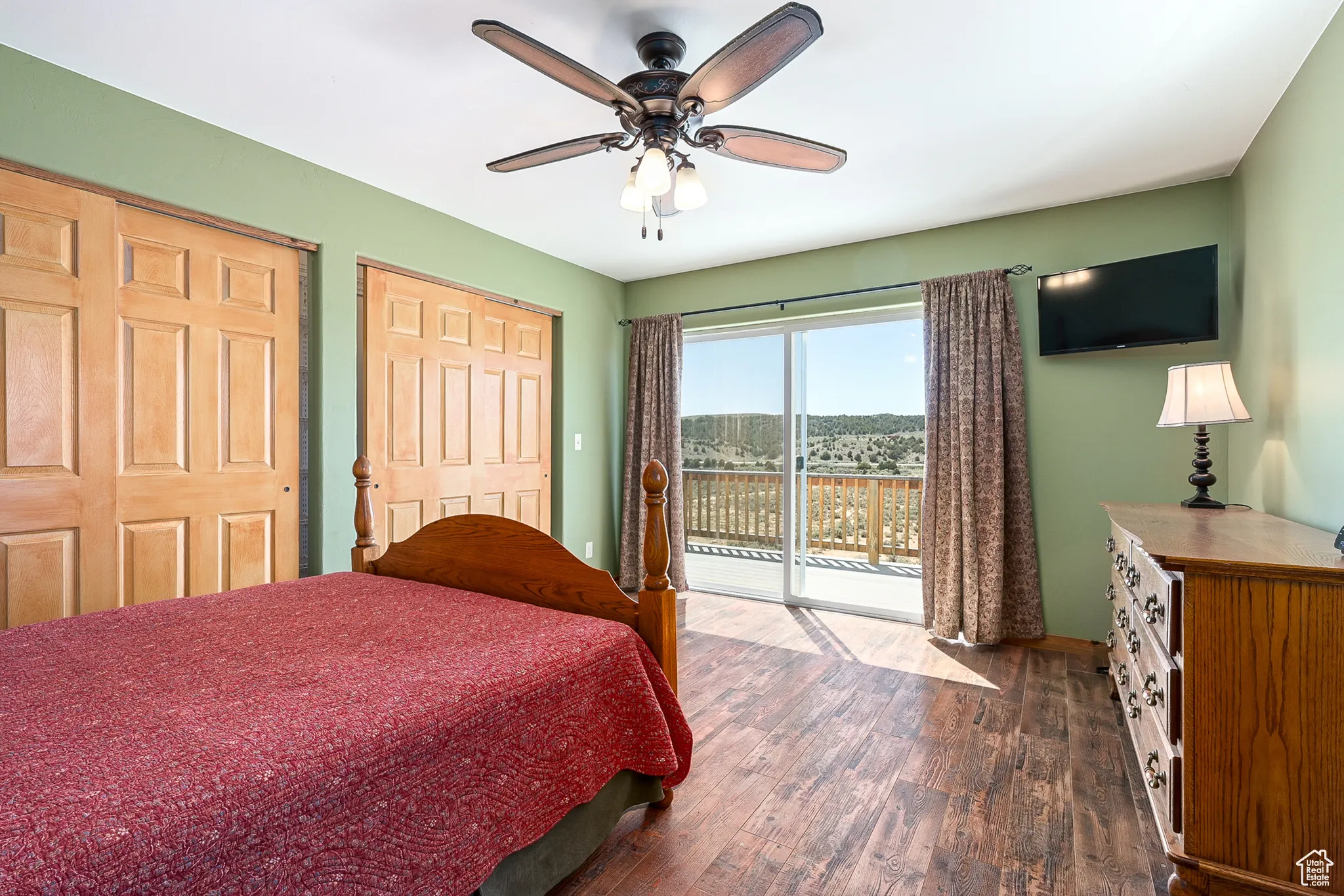 Barn upstairs apartment bedroom featuring access to outside, dark wood-type flooring, ceiling fan, two closets, and baseboards