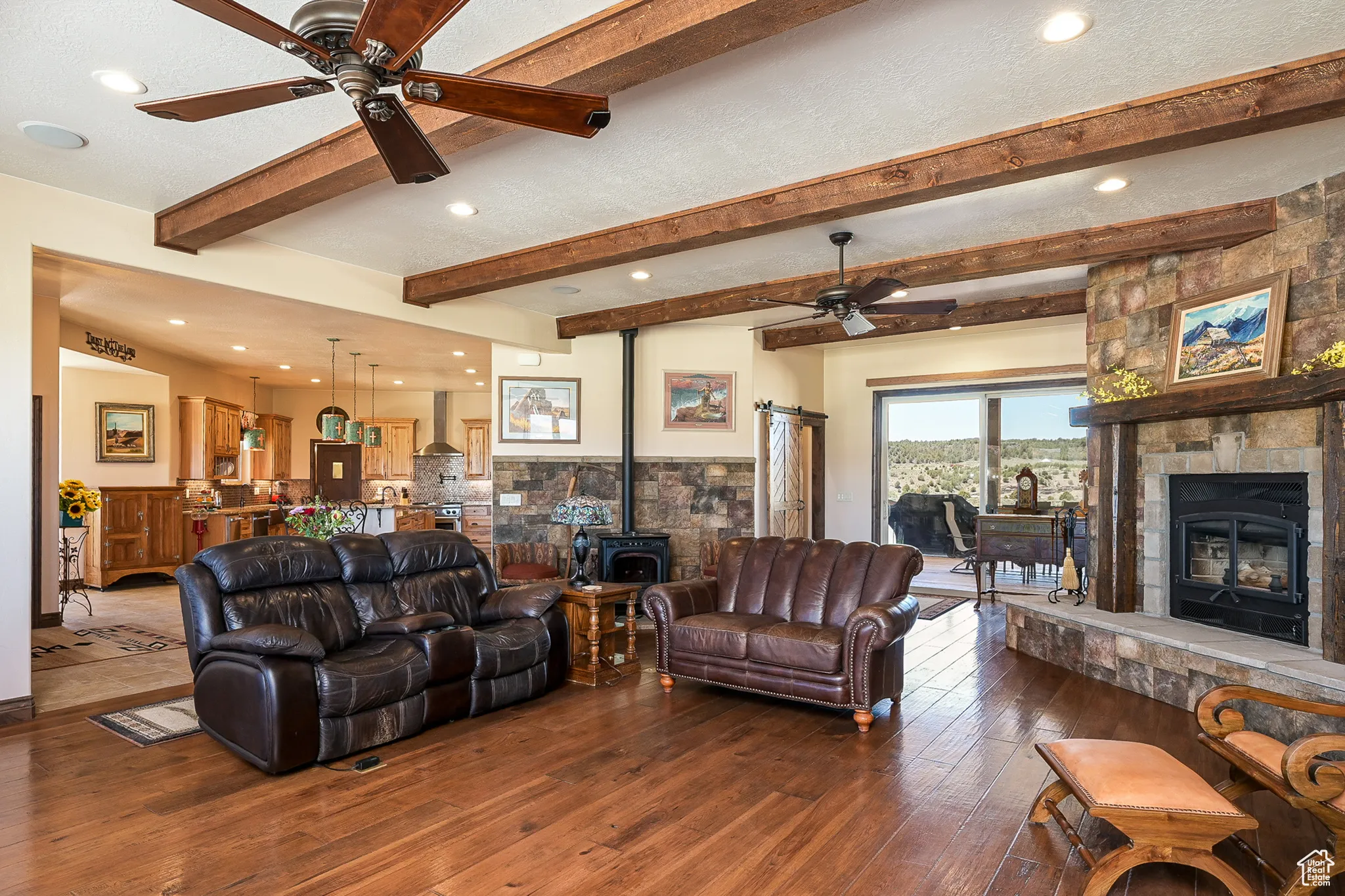 Living room featuring a wood stove, ceiling fan, hardwood / wood-style floors, beamed ceiling, and recessed lighting