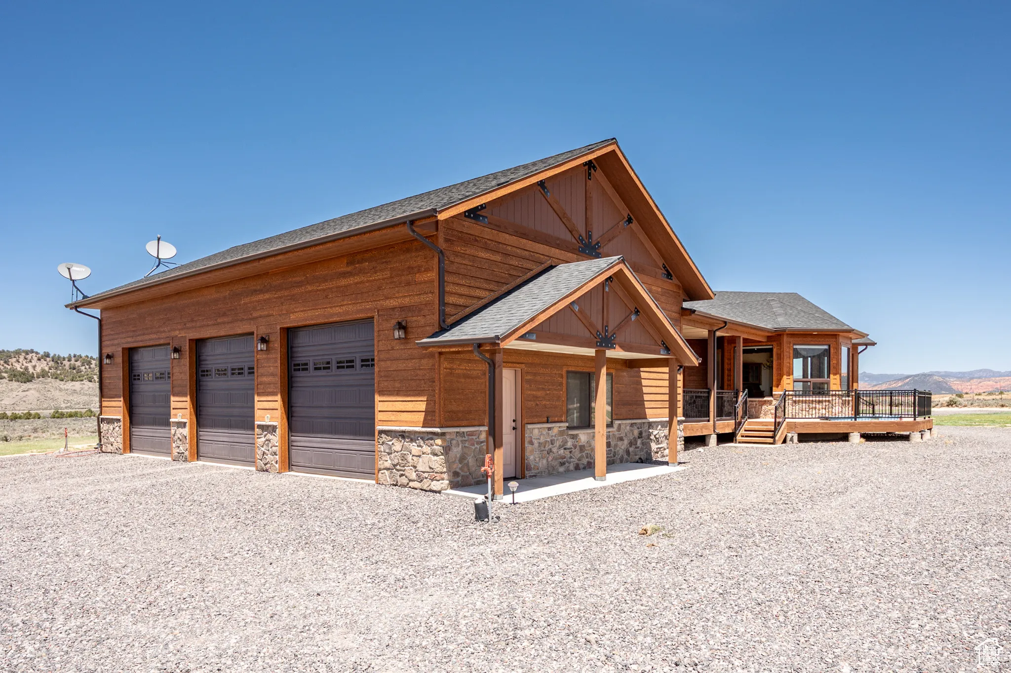 View of side of property with stone siding, covered porch, a mountain view, and a shingled roof
