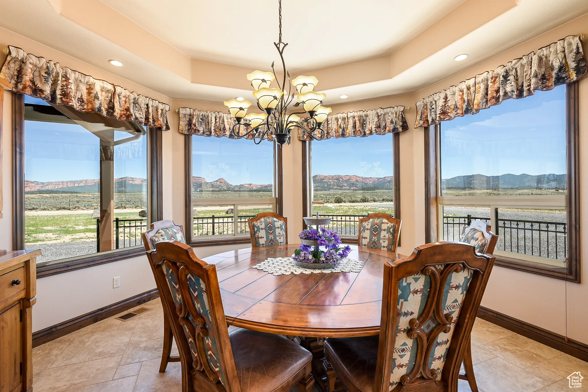 Dining room featuring a chandelier, a raised ceiling, baseboards, a mountain view, and recessed lighting