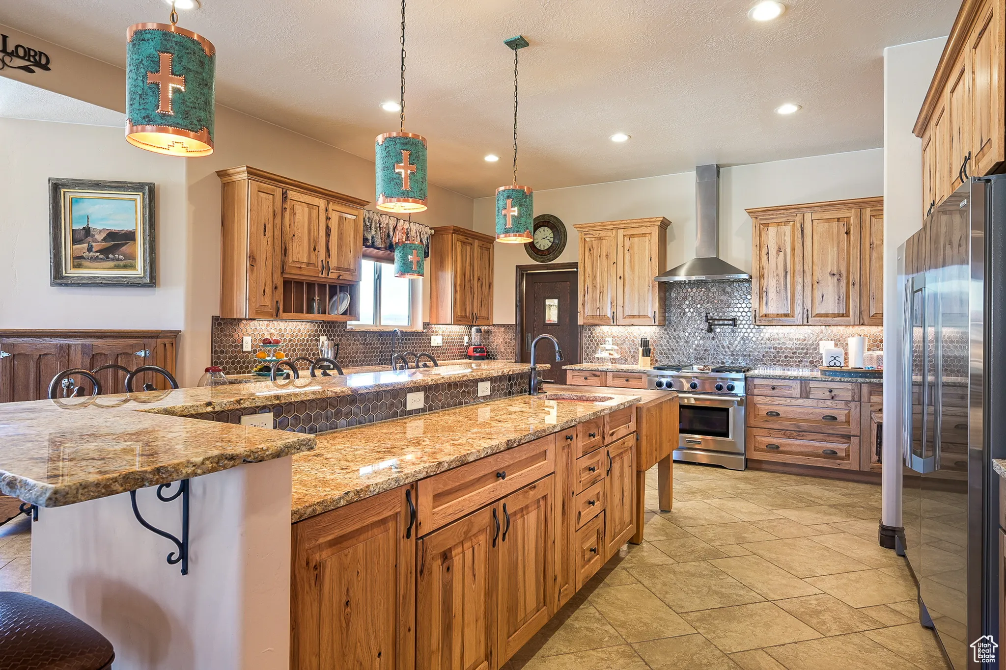 Kitchen featuring stainless steel appliances, wall chimney exhaust hood, a sink, a breakfast bar area, and decorative backsplash