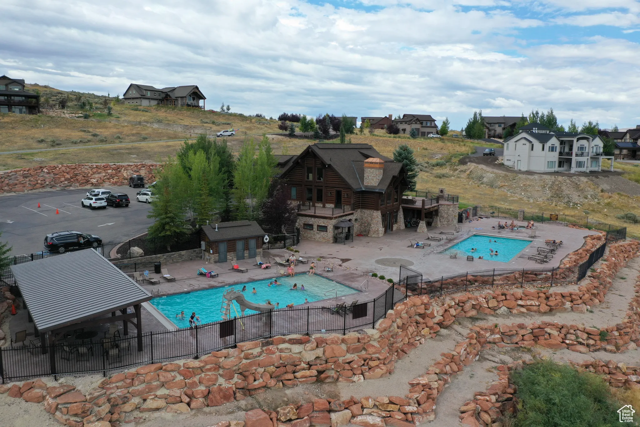 Community pool with fence, a jacuzzi, a patio area, and an outbuilding