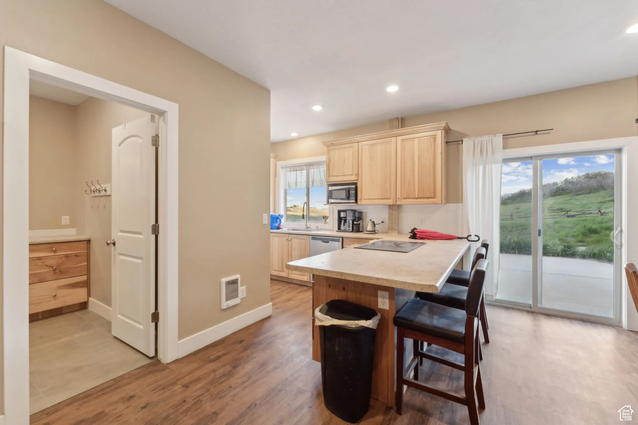 Roper Barn | Kitchen featuring light brown cabinets, stainless steel appliances, light countertops, a breakfast bar area, and light wood-style floors | Conditioned Use
