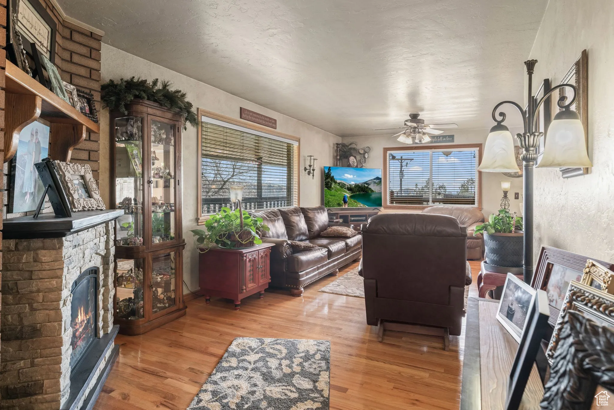 Living area featuring a fireplace, a ceiling fan, wood finished floors, and a textured ceiling