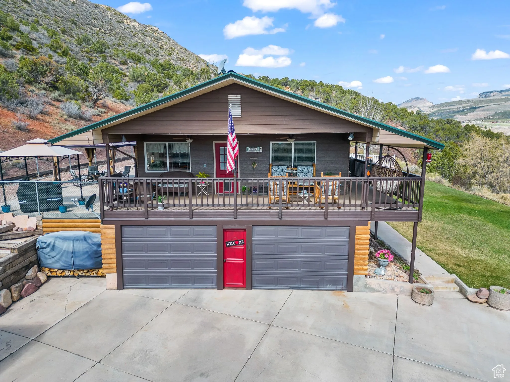 View of front facade with a garage, a mountain view, driveway, ceiling fan, and a front lawn