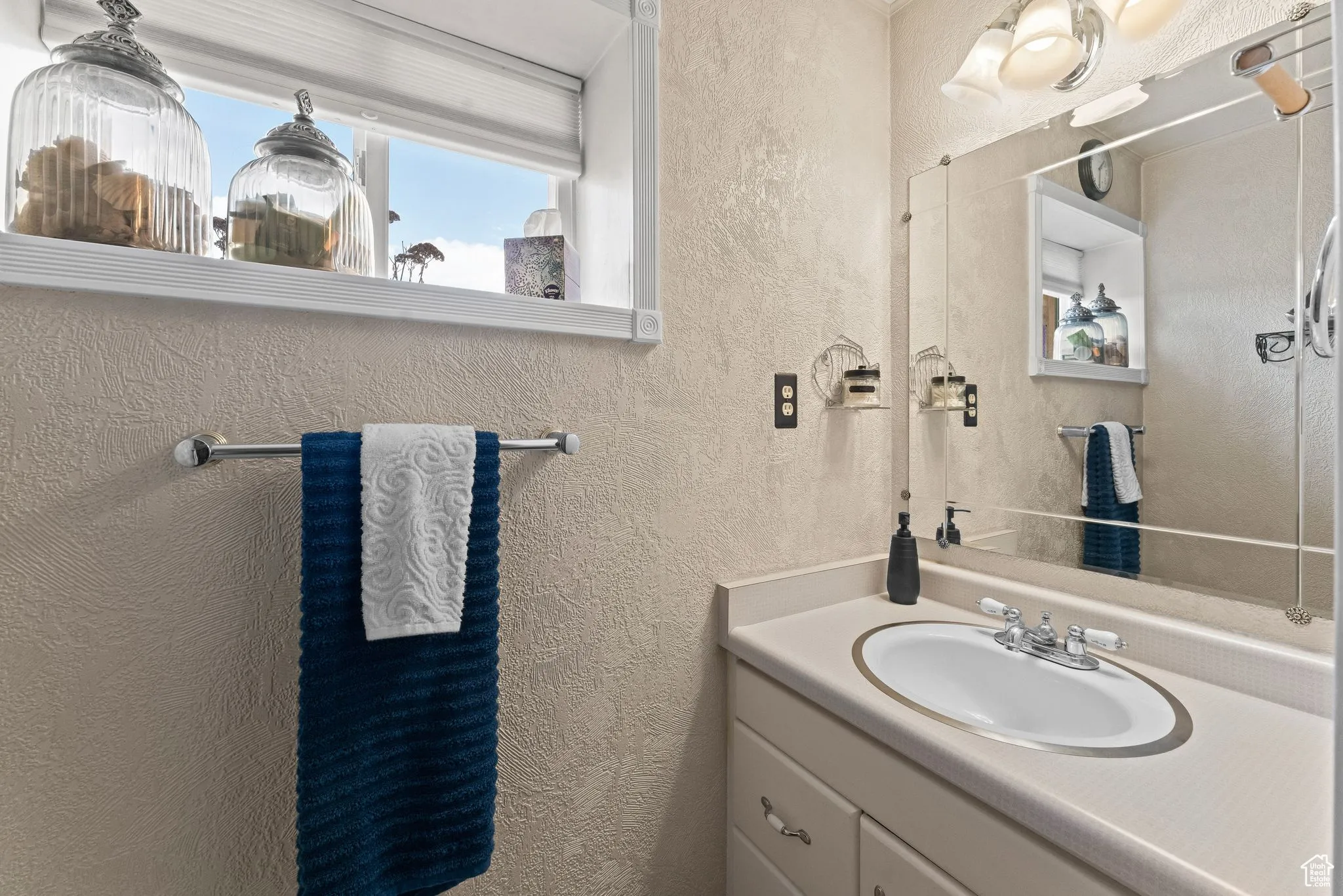 Bathroom featuring a textured wall and vanity