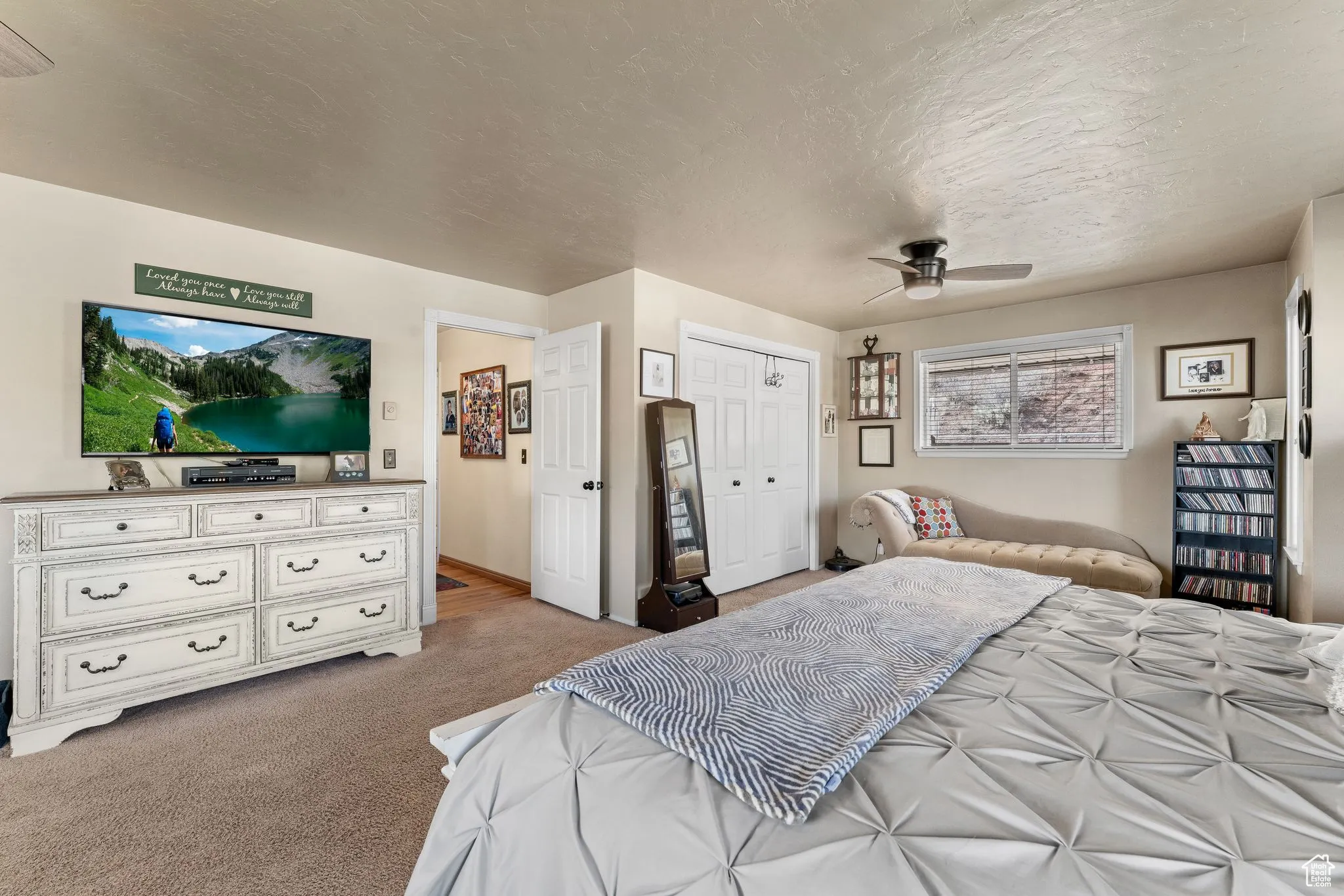 Bedroom with light colored carpet, a closet, a textured ceiling, and a ceiling fan