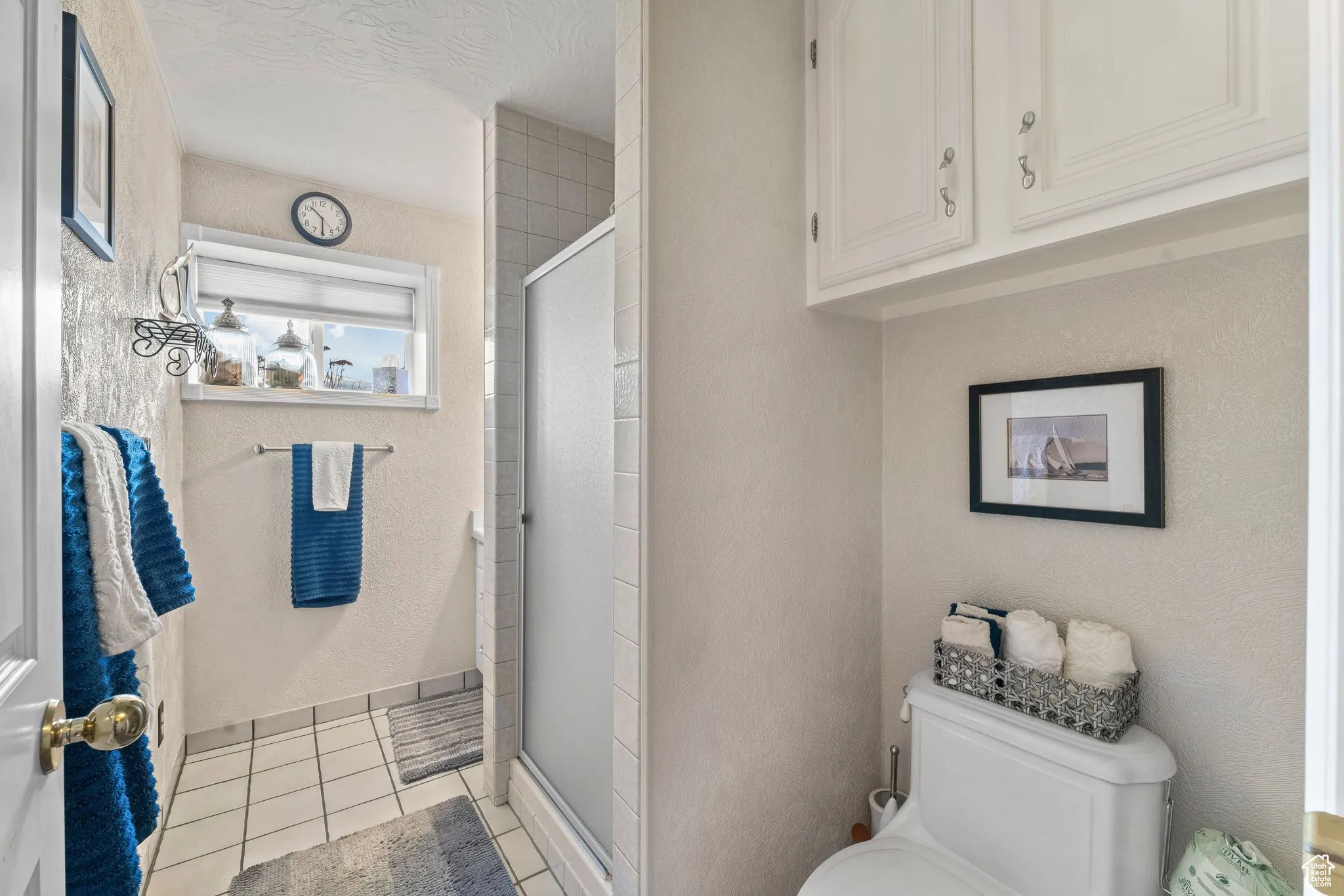 Full bath featuring toilet, a shower stall, and tile patterned flooring