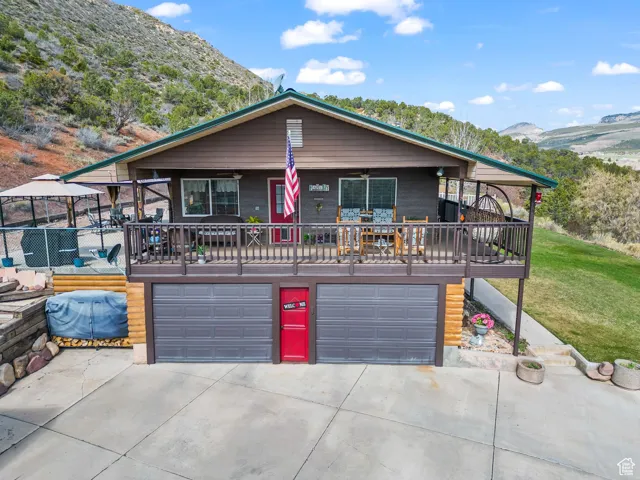 View of front facade with a garage, a mountain view, driveway, ceiling fan, and a front lawn
