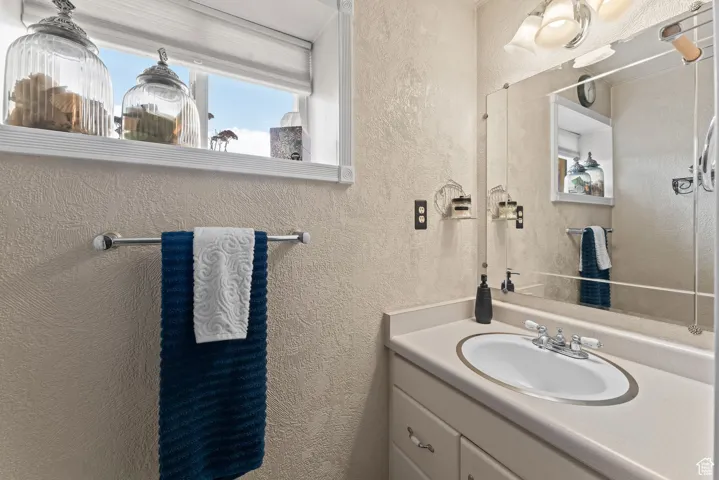 Bathroom featuring a textured wall and vanity