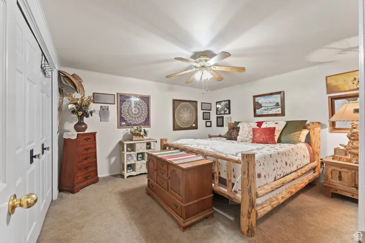 Bedroom with light colored carpet, a closet, and a ceiling fan