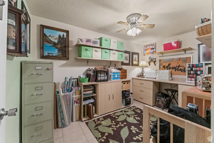 Office area with ceiling fan, light tile patterned floors, and a textured ceiling
