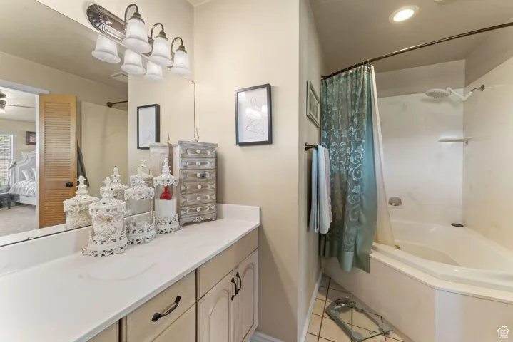 Bathroom featuring tile patterned floors, shower / bath combination with curtain, vanity, ensuite bath, and baseboards
