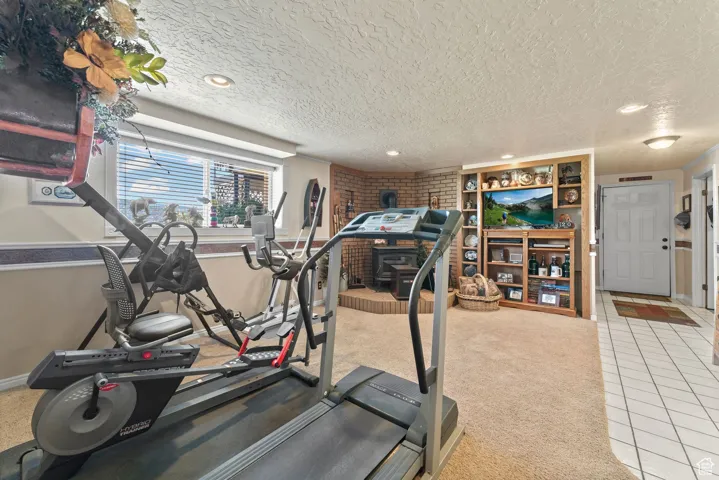 Workout area featuring tile patterned floors, a textured ceiling, recessed lighting, baseboards, and carpet flooring