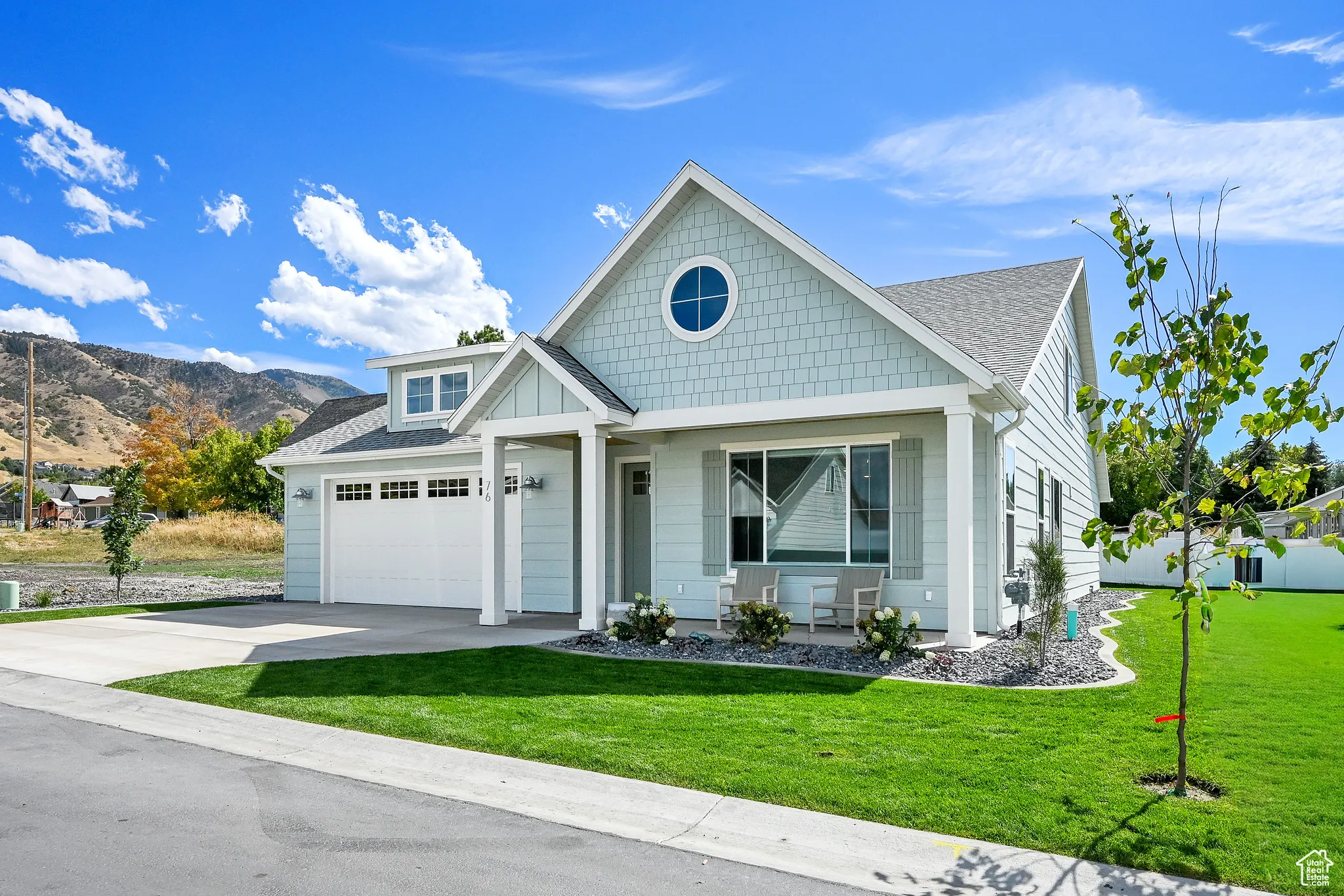 View of front of house featuring a front yard, a shingled roof, and driveway