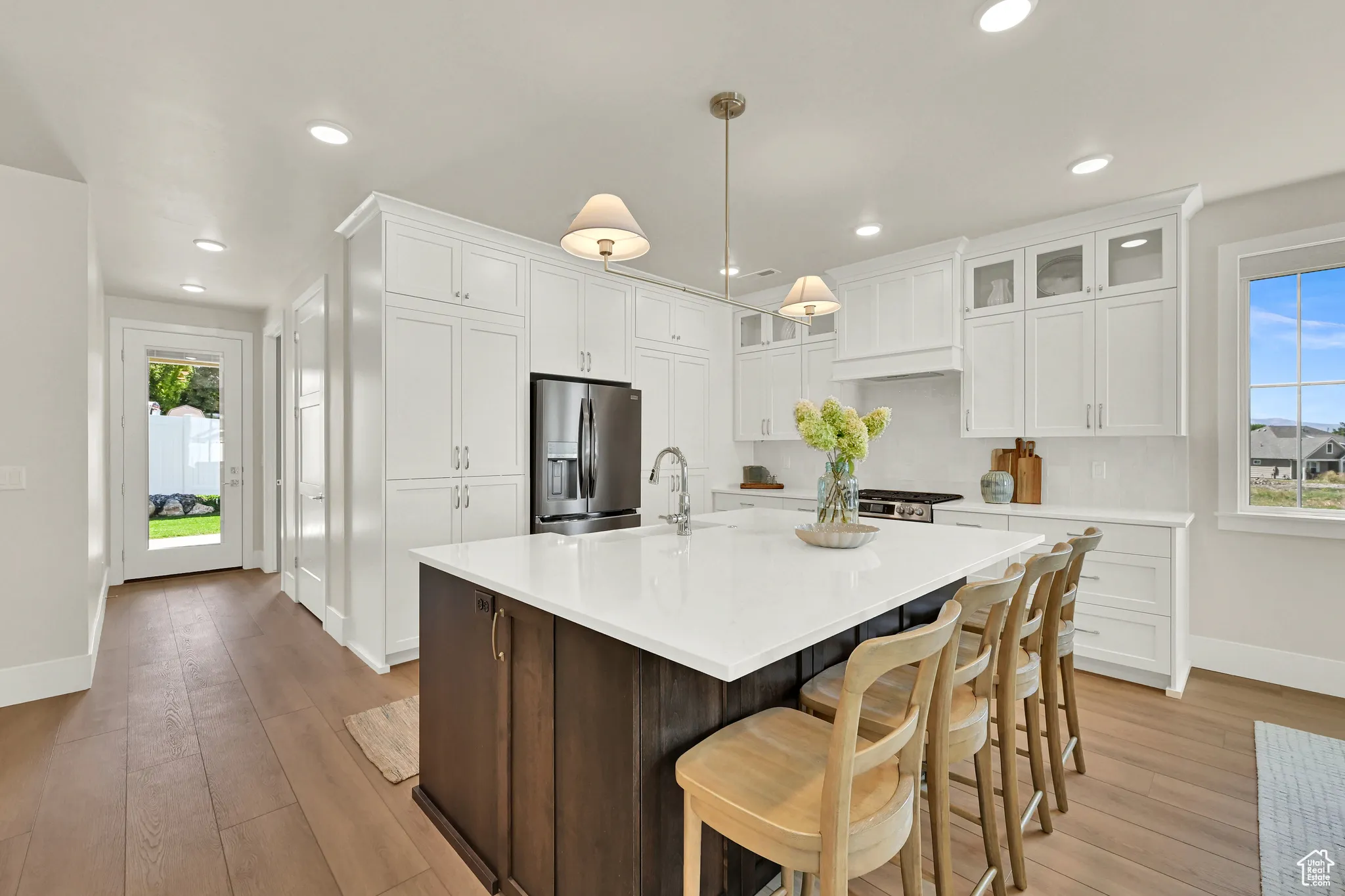 Kitchen featuring dark brown cabinets, stainless steel refrigerator with ice dispenser, white cabinets, an island with sink, and a kitchen breakfast bar