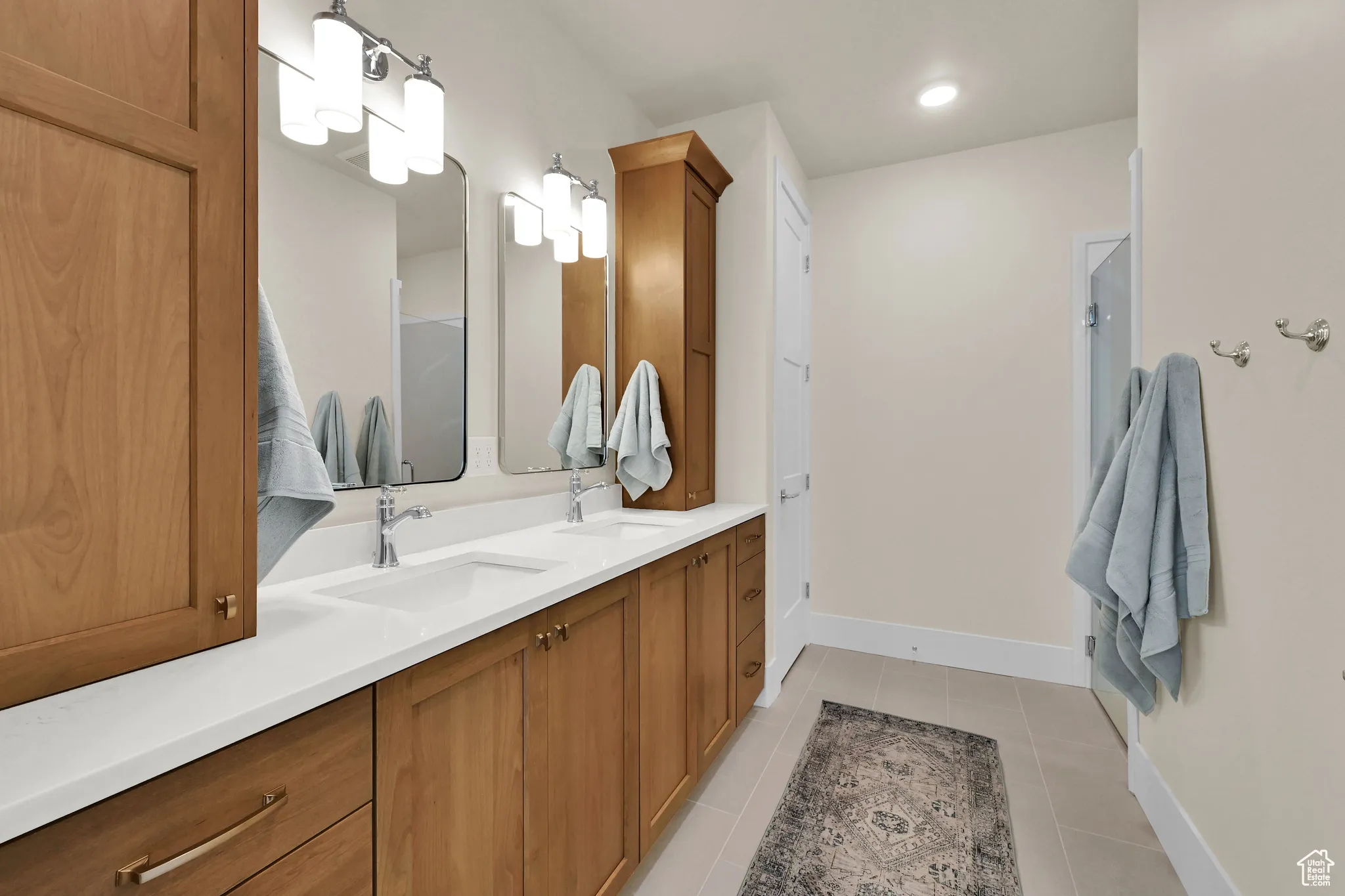 Bathroom with light tile patterned flooring, double vanity, and a stall shower