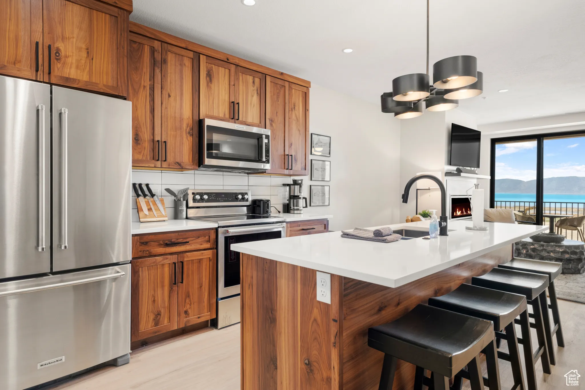 Kitchen featuring appliances with stainless steel finishes, brown cabinets, a sink, light countertops, and open floor plan